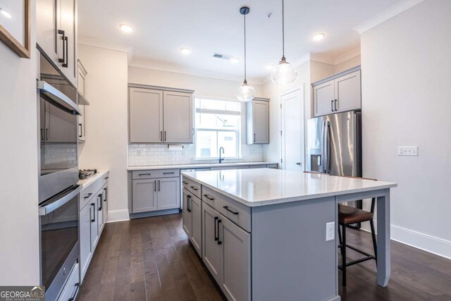 kitchen with stainless steel appliances, a center island, gray cabinets, and decorative light fixtures