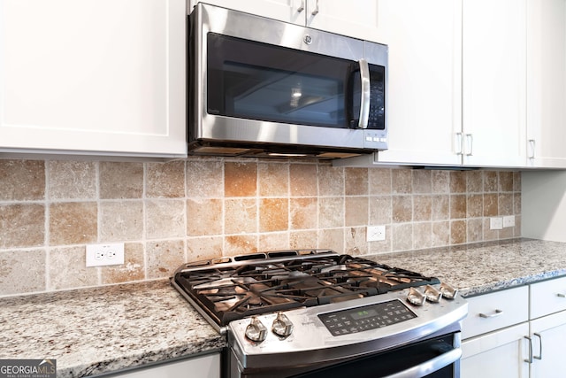 kitchen featuring white cabinetry, stainless steel appliances, light stone countertops, and backsplash