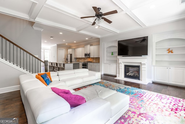 living room featuring dark wood-type flooring, ceiling fan, coffered ceiling, and built in shelves