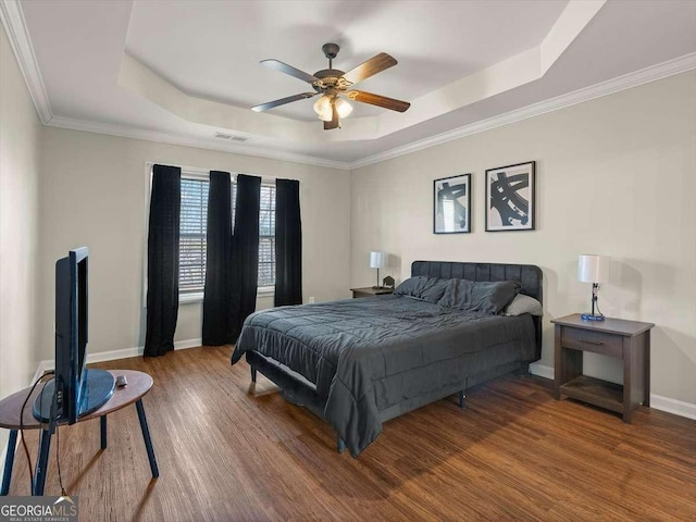 bedroom with a raised ceiling, crown molding, hardwood / wood-style flooring, and ceiling fan