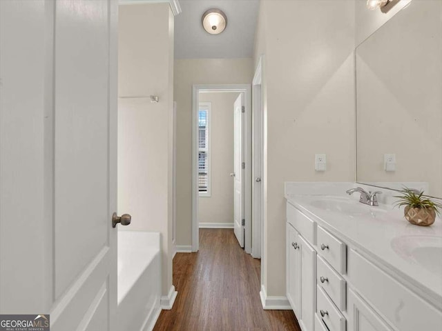 bathroom with hardwood / wood-style flooring, vanity, and a bath