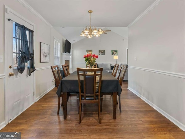 dining area featuring dark wood-type flooring, lofted ceiling, crown molding, and an inviting chandelier