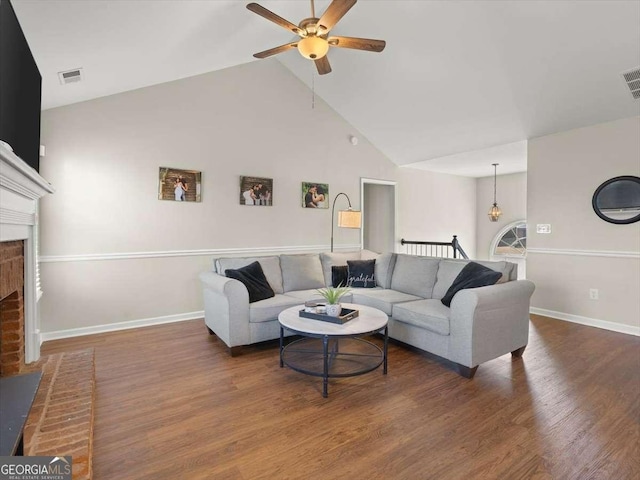 living room featuring a brick fireplace, dark wood-type flooring, high vaulted ceiling, and ceiling fan