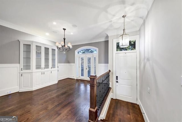 entrance foyer featuring dark hardwood / wood-style flooring, a notable chandelier, ornamental molding, and french doors