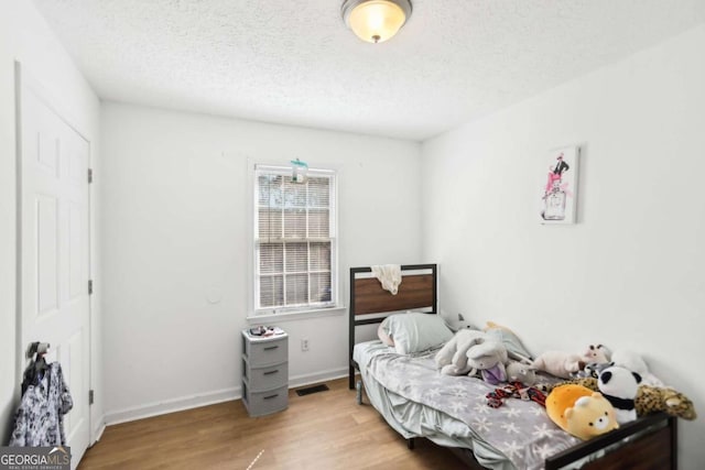 bedroom with a textured ceiling and light wood-type flooring