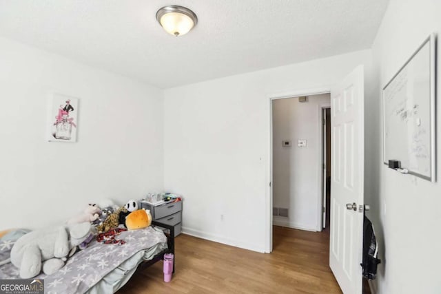 bedroom featuring light hardwood / wood-style floors and a textured ceiling