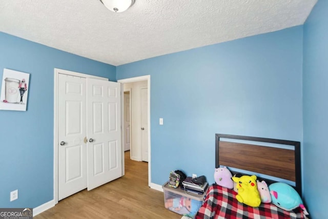 bedroom featuring a closet, light hardwood / wood-style flooring, and a textured ceiling