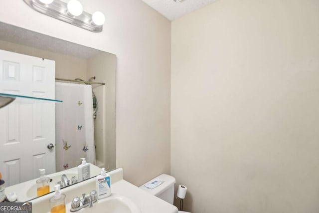 bathroom with walk in shower, vanity, a textured ceiling, and toilet