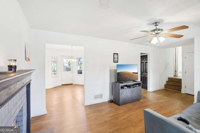 living room featuring wood-type flooring and ceiling fan with notable chandelier