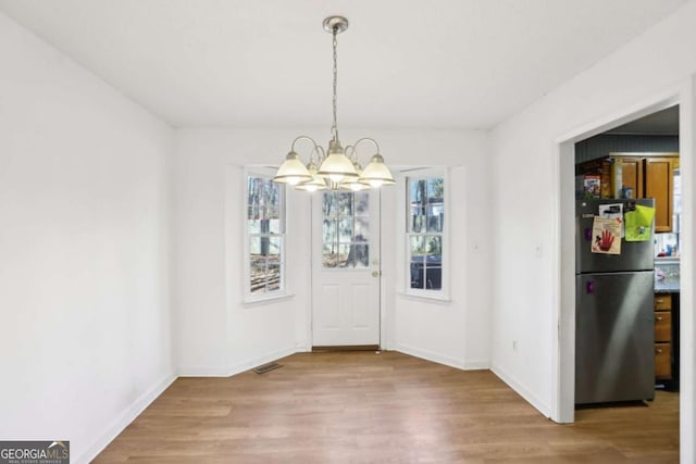 unfurnished dining area with hardwood / wood-style flooring and a chandelier