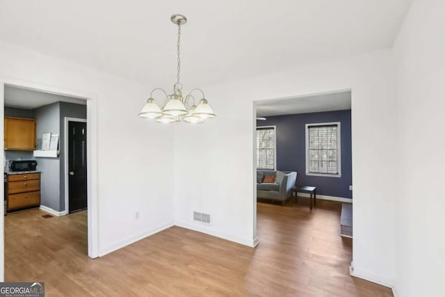 unfurnished dining area featuring hardwood / wood-style floors and a chandelier