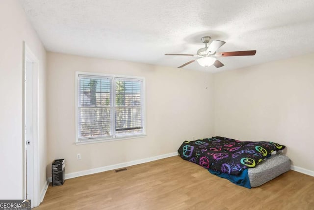 bedroom featuring ceiling fan, a textured ceiling, and light wood-type flooring