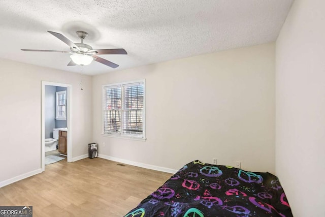 bedroom with ceiling fan, connected bathroom, a textured ceiling, and light hardwood / wood-style flooring