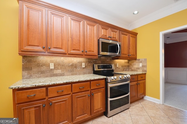 kitchen with stainless steel appliances, crown molding, light stone countertops, and light tile patterned floors