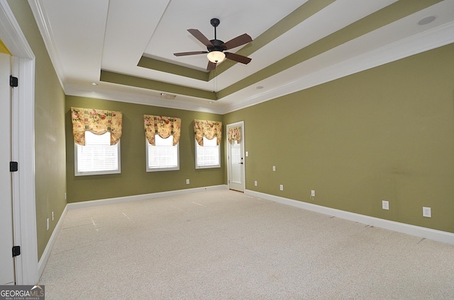 carpeted empty room featuring crown molding, ceiling fan, and a tray ceiling