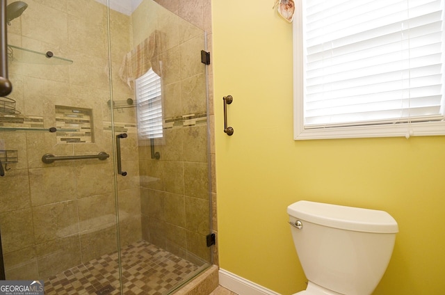 bathroom featuring toilet and a shower with shower door