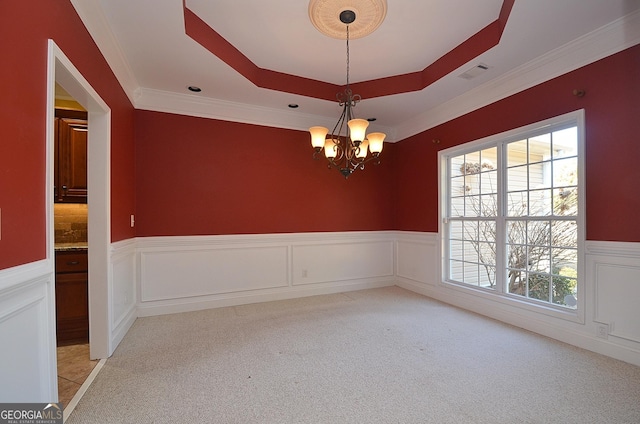 spare room with a chandelier, light colored carpet, and a raised ceiling