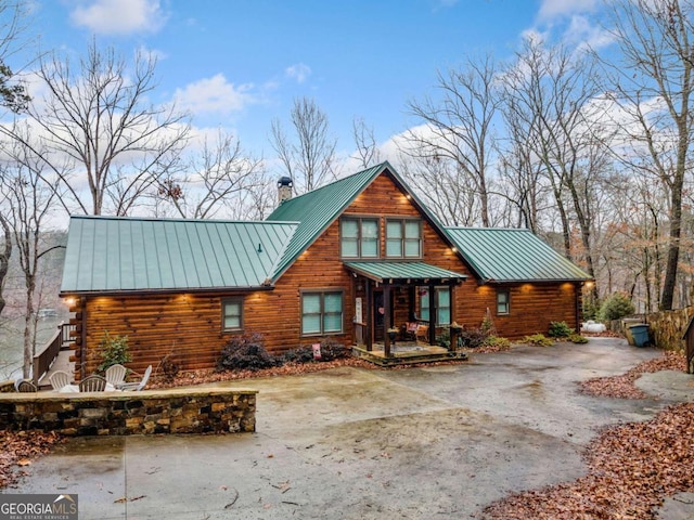 log cabin with metal roof, driveway, log siding, a standing seam roof, and a chimney