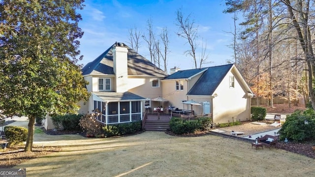 rear view of house with a sunroom, a deck, and a lawn