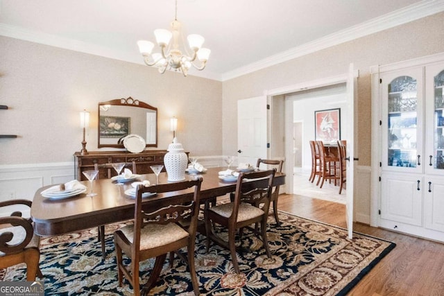 dining area featuring crown molding, hardwood / wood-style floors, and a notable chandelier