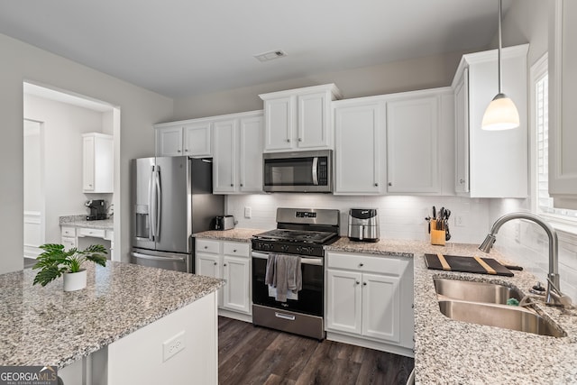 kitchen featuring stainless steel appliances, white cabinetry, hanging light fixtures, and sink