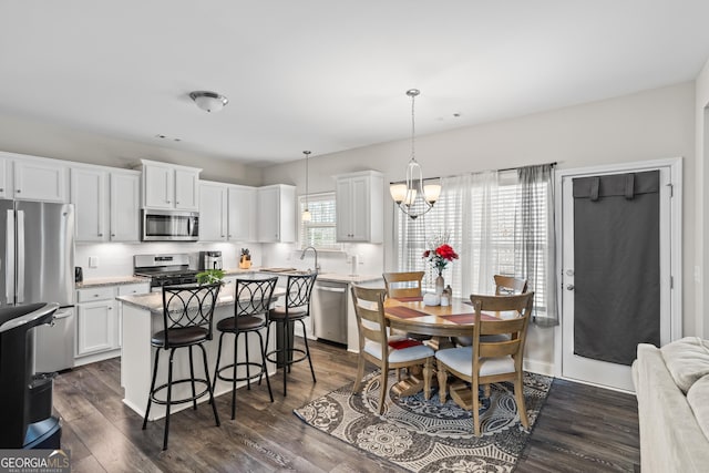 kitchen with white cabinetry, hanging light fixtures, stainless steel appliances, a center island, and dark hardwood / wood-style flooring