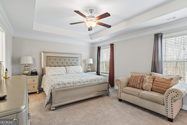 bedroom featuring crown molding, a tray ceiling, light colored carpet, and ceiling fan