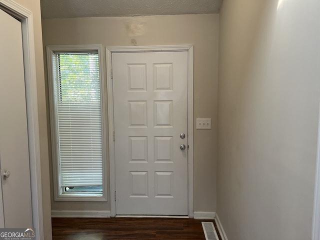 doorway to outside featuring dark hardwood / wood-style flooring and a textured ceiling