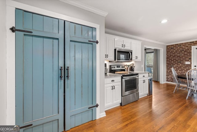 kitchen with ornamental molding, appliances with stainless steel finishes, white cabinets, and dark hardwood / wood-style flooring