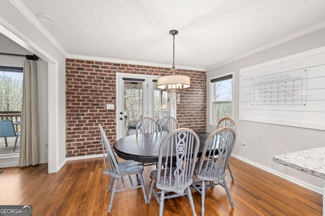 dining space featuring ornamental molding, brick wall, a chandelier, and dark hardwood / wood-style flooring