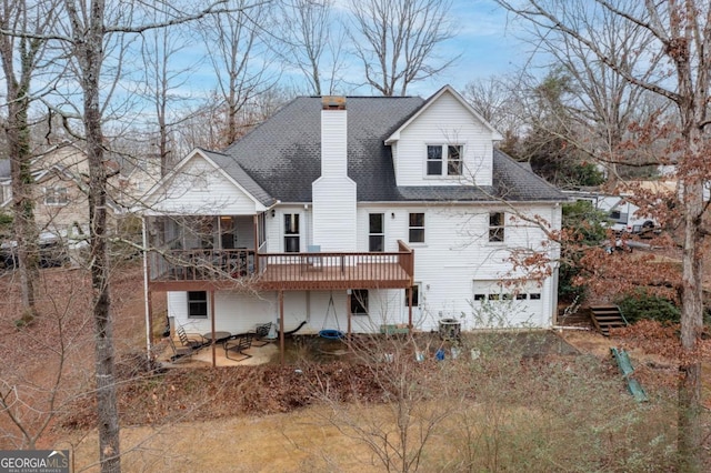 rear view of property with a wooden deck and a garage