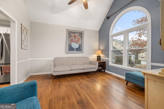 living room with hardwood / wood-style flooring, vaulted ceiling, and ceiling fan