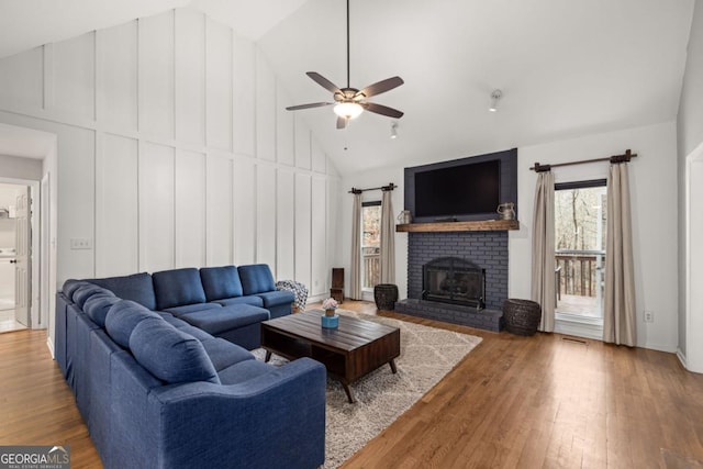 living room featuring hardwood / wood-style floors, a fireplace, high vaulted ceiling, and ceiling fan