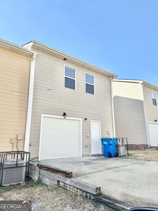 rear view of house with central AC and a garage