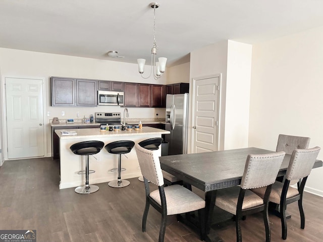 kitchen featuring sink, a breakfast bar, dark brown cabinets, stainless steel appliances, and dark hardwood / wood-style floors