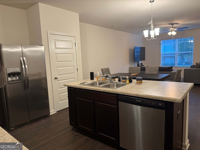 kitchen featuring pendant lighting, sink, dark wood-type flooring, appliances with stainless steel finishes, and a kitchen island with sink