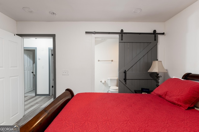 bedroom featuring wood-type flooring and a barn door