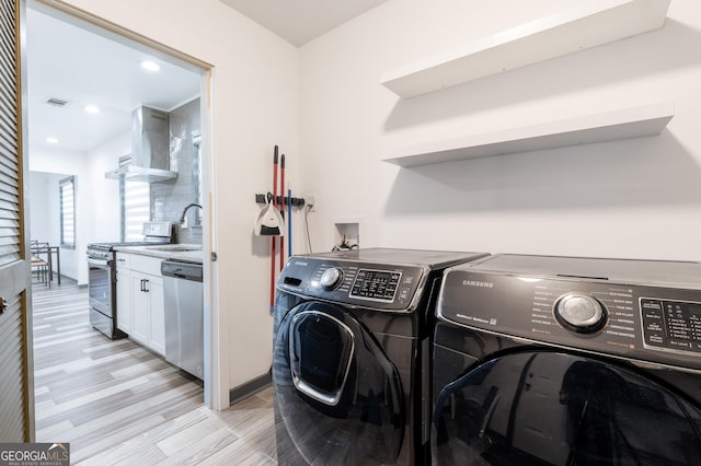 washroom featuring light hardwood / wood-style floors, separate washer and dryer, and sink