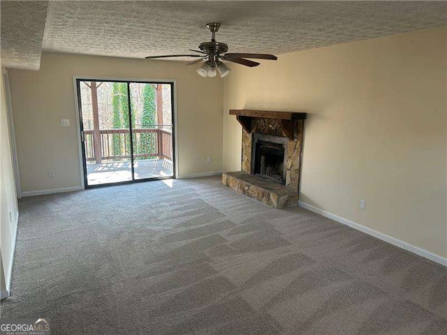 unfurnished living room featuring ceiling fan, a stone fireplace, carpet floors, and a textured ceiling