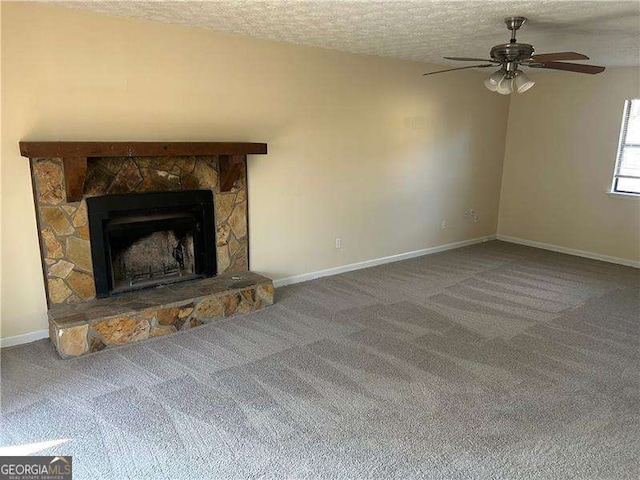 unfurnished living room featuring ceiling fan, a stone fireplace, a textured ceiling, and carpet