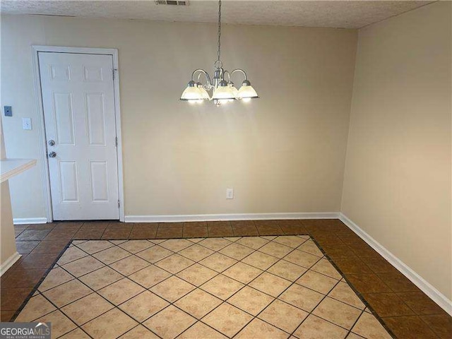 unfurnished dining area featuring a notable chandelier, tile patterned floors, and a textured ceiling