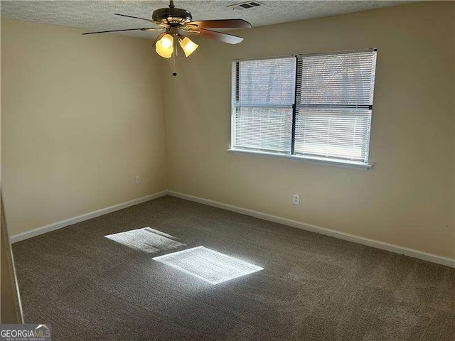 unfurnished room with ceiling fan, dark carpet, and a textured ceiling