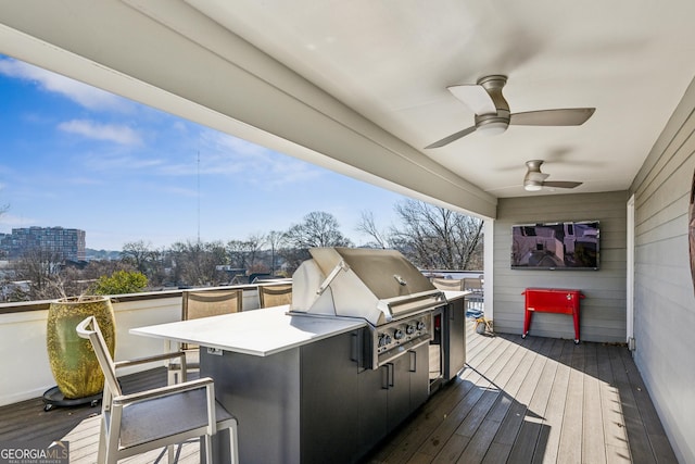 wooden terrace featuring ceiling fan, an outdoor kitchen, an outdoor bar, and area for grilling