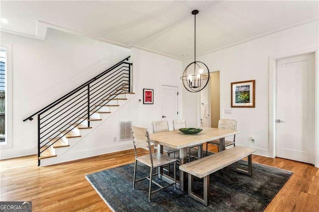 dining space with hardwood / wood-style floors and a notable chandelier