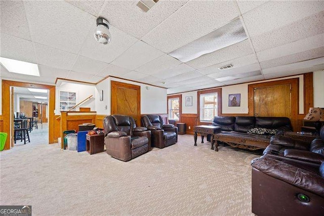 living room featuring a paneled ceiling, wooden walls, and carpet