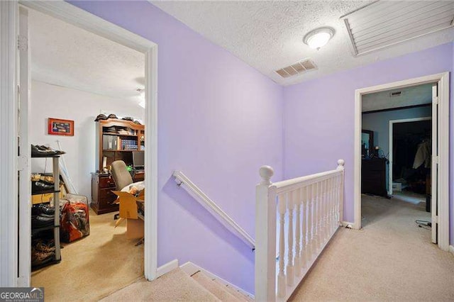 hallway featuring light carpet and a textured ceiling