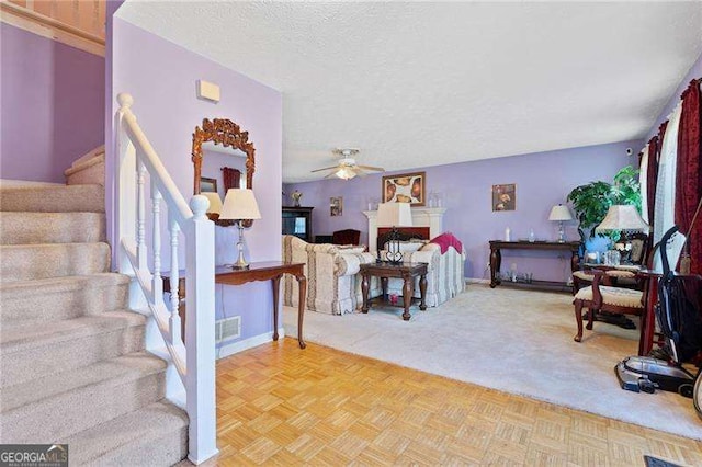 carpeted living room featuring ceiling fan and a textured ceiling