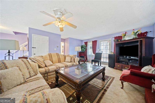 carpeted living room featuring ceiling fan and a textured ceiling