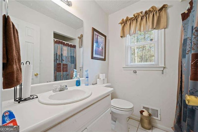 bathroom featuring vanity, tile patterned flooring, a textured ceiling, and toilet