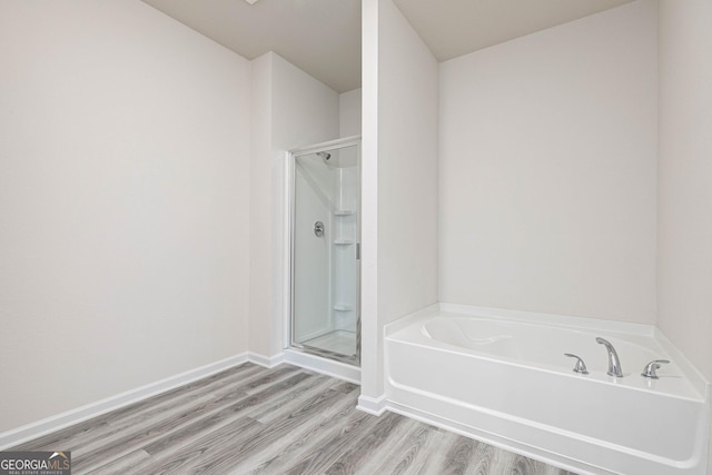 bathroom featuring wood-type flooring and separate shower and tub